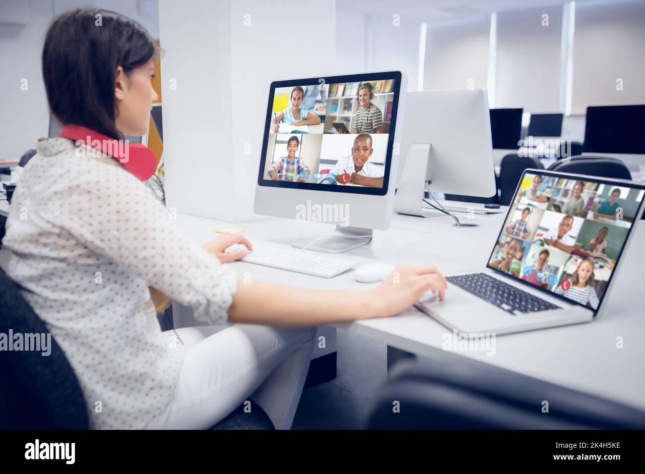 Female teacher wearing headphones having a video call with multiple ...