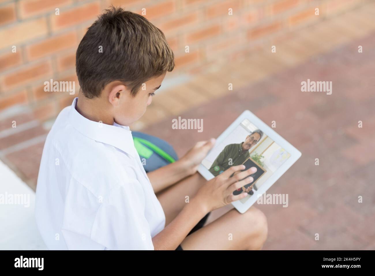 Male caucasian student having a video call with male teacher on digital ...