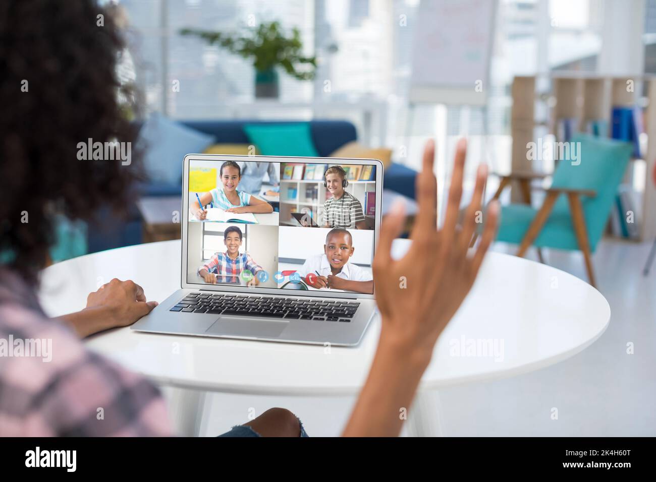 Mixed race female teacher using laptop on video call with school ...