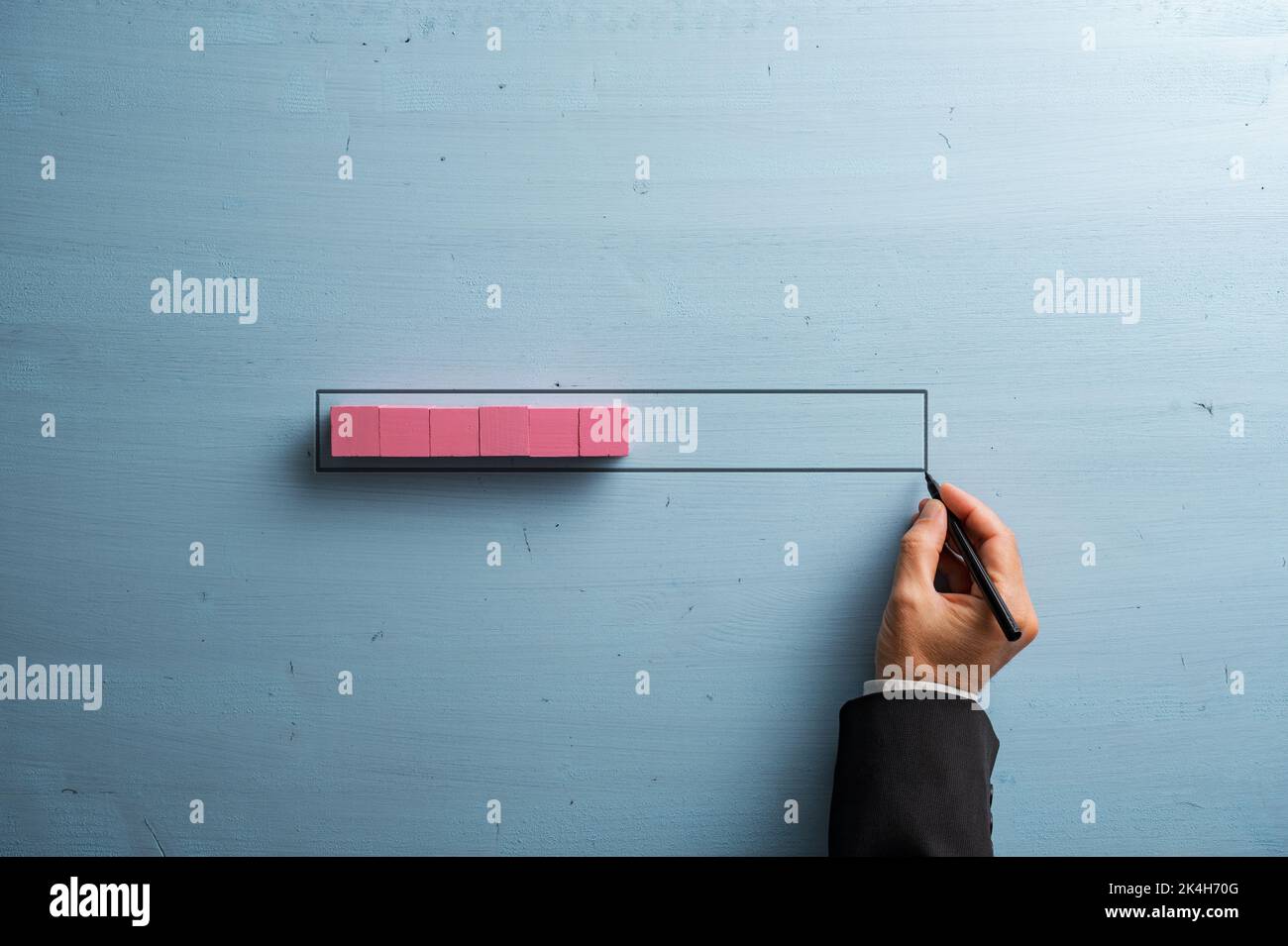Male hand drawing a loading bar with pink wooden blocks representing