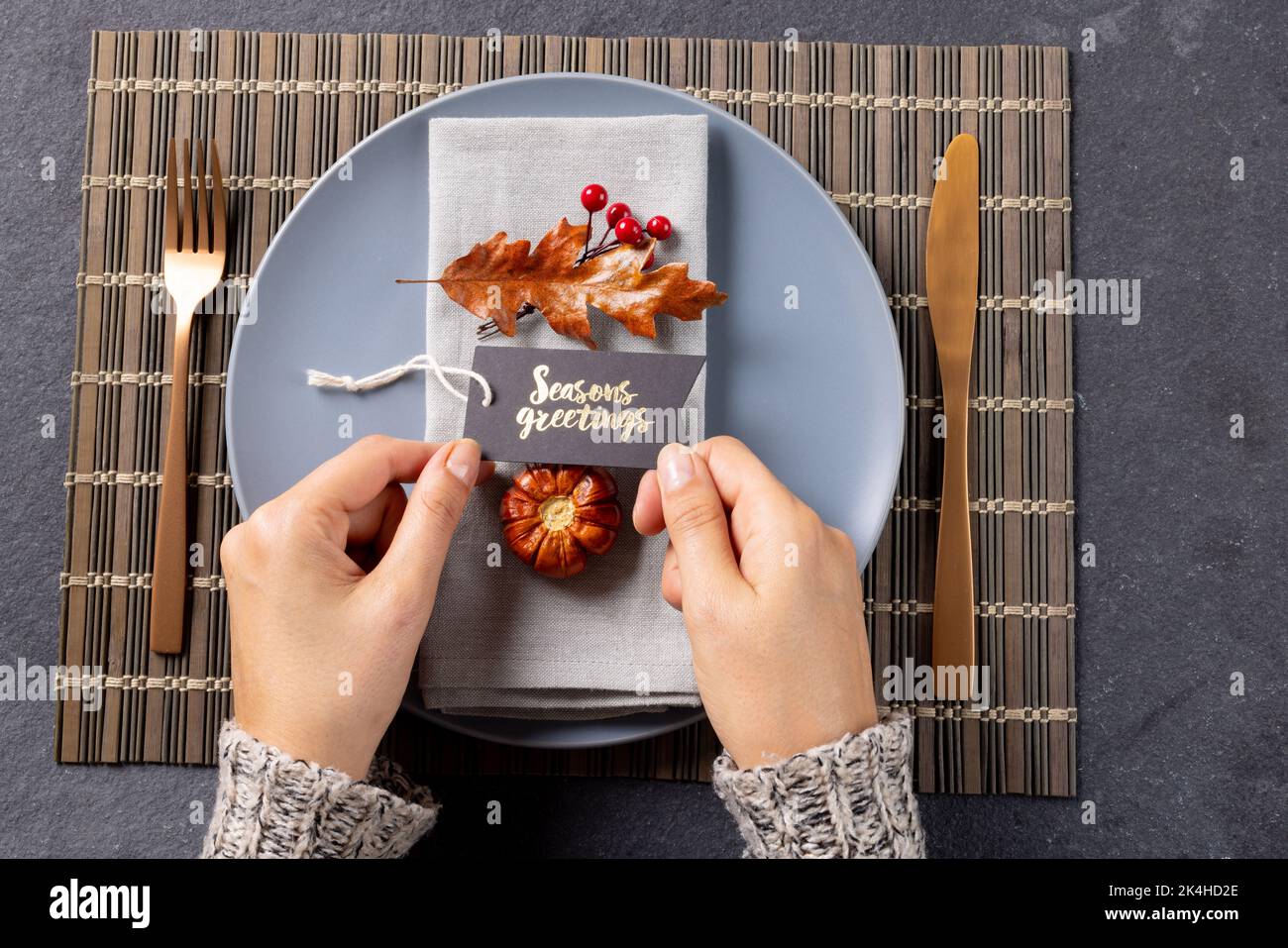 Overhead view of thanksgiving place setting with caucasian woman holding greetings tag on slate Stock Photo
