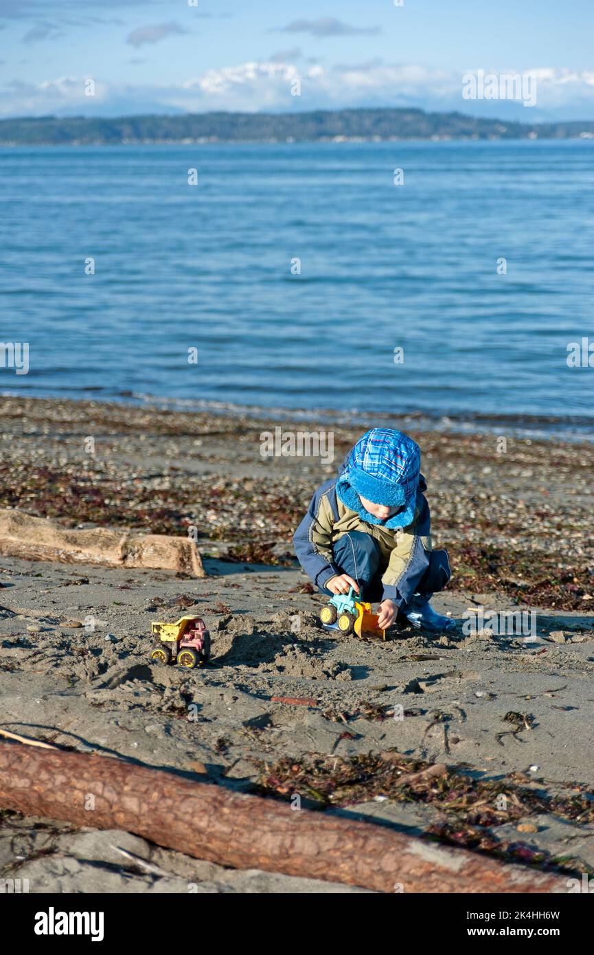 Boy playing with toy truck on beach. Stock Photo