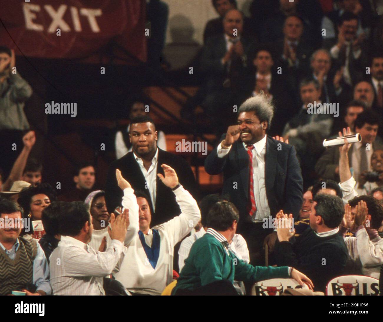 Boxing promoter Don King and heavyweight boxing champion Mike Tyson wave to the crowd while attending a Chicago Bulls basketball game, ca. 1990 Stock Photo