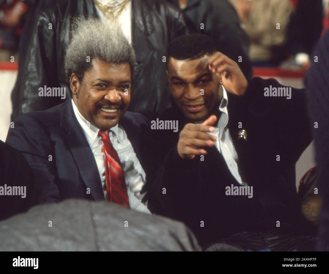 Boxing promoter Don King and heavyweight boxing champion Mike Tyson gesture to photographers while attending a Chicago Bulls basketball game, ca. 1990 Stock Photo