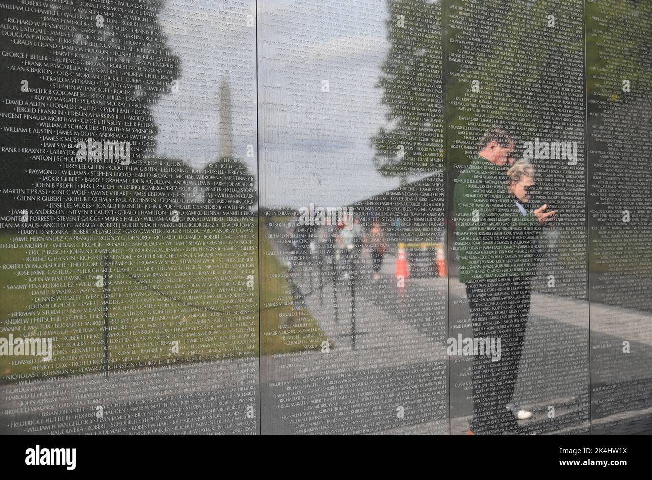 People are reflected in the names of the fallen on the black granite at the Vietnam Memorial Wall in Washington, DC. Stock Photo