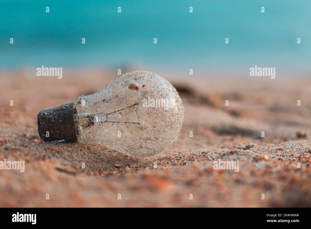 Glass light bulb pollution on the beach. Environmental Pollution. Global Warming. Save Earth. Stock Photo