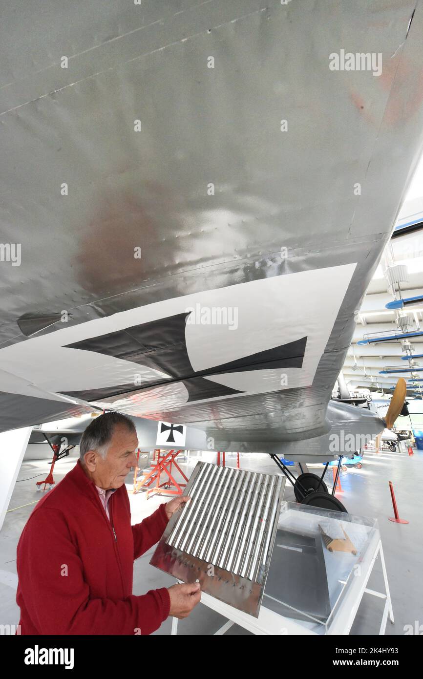 29 September 2022, Saxony-Anhalt, Dessau-Roßlau: In the 'Hugo Junkers' Museum of Technology, honorary managing director and former commercial pilot Gerd Fucke of the Förderverein Technikmuseum Hugo Junkers e.V. stands at the replica of the first all-metal airplane in the world, a J1 from 1915. The airplane, which did not go into series production, was rebuilt by the members of the Förderverein only from overview drawings and detail photos using tin can sheeting. It is one of the special exhibits dedicated to the aircraft designer and entrepreneur Hugo Junkers (Hugo Junkers born February 3, 185 Stock Photo
