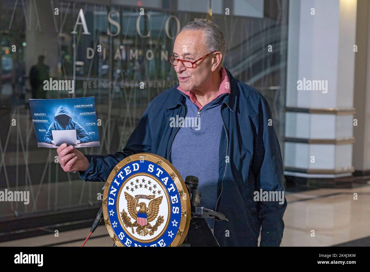NEW YORK, NY – OCTOBER 02: Senate Majority Leader, U.S. Senator Chuck Schumer (D-NY) holds up a sign with a symbolic hacker on it on October 2, 2022 in New York City. New York Senator Chuck Schumer is calling on the federal government to release more information about recent data breaches, and to increase their efforts to protect consumers from cyber security breaches and investigate those responsible for such hacks. Credit: Ron Adar/Alamy Live News Stock Photo