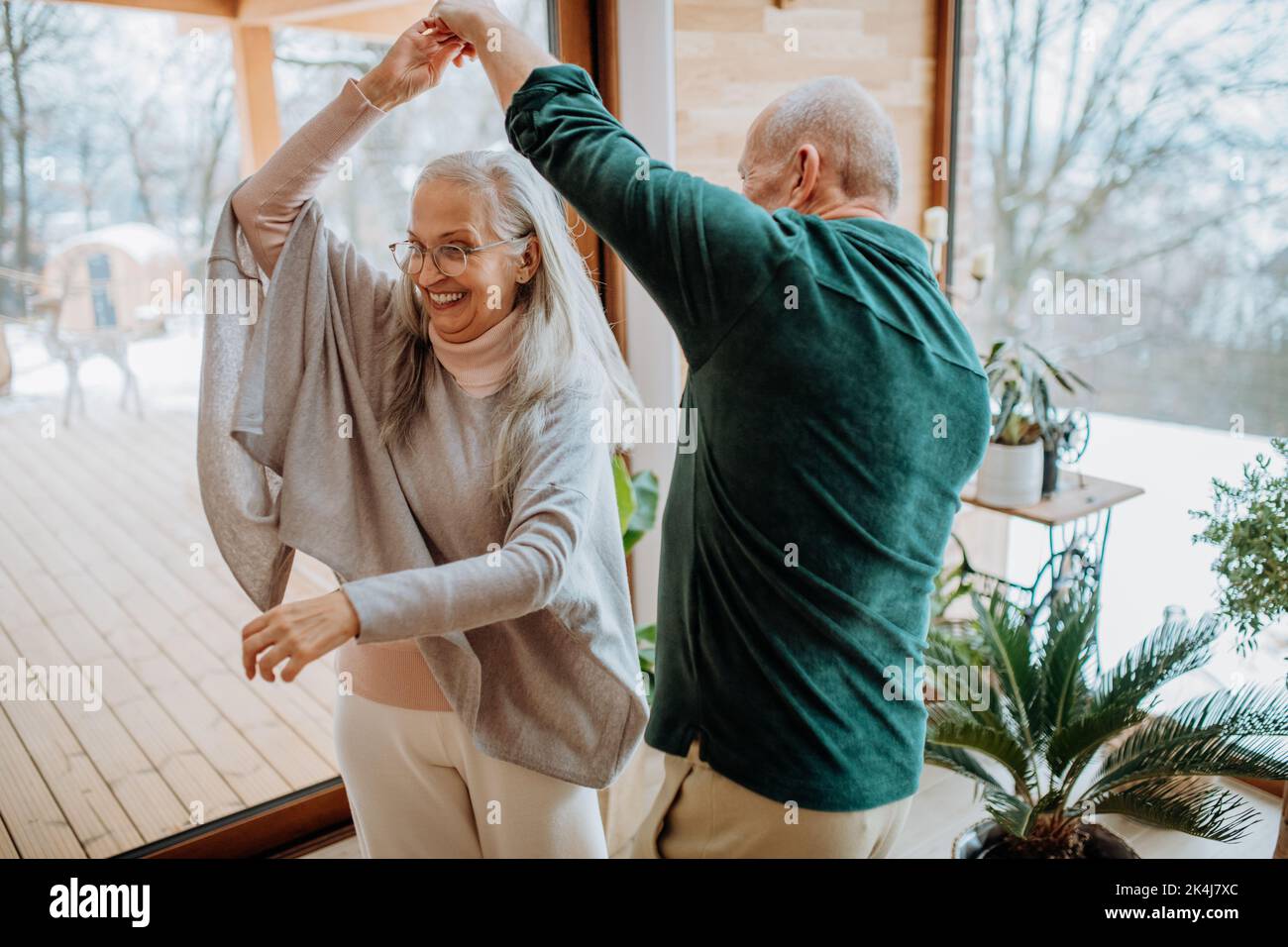 Senior couple in love dancing together in their modern living room. Stock Photo