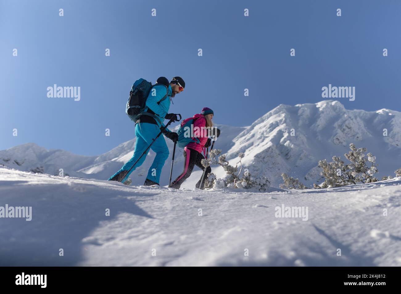 Low angle view of ski touring couple hiking up in mountains. Stock Photo