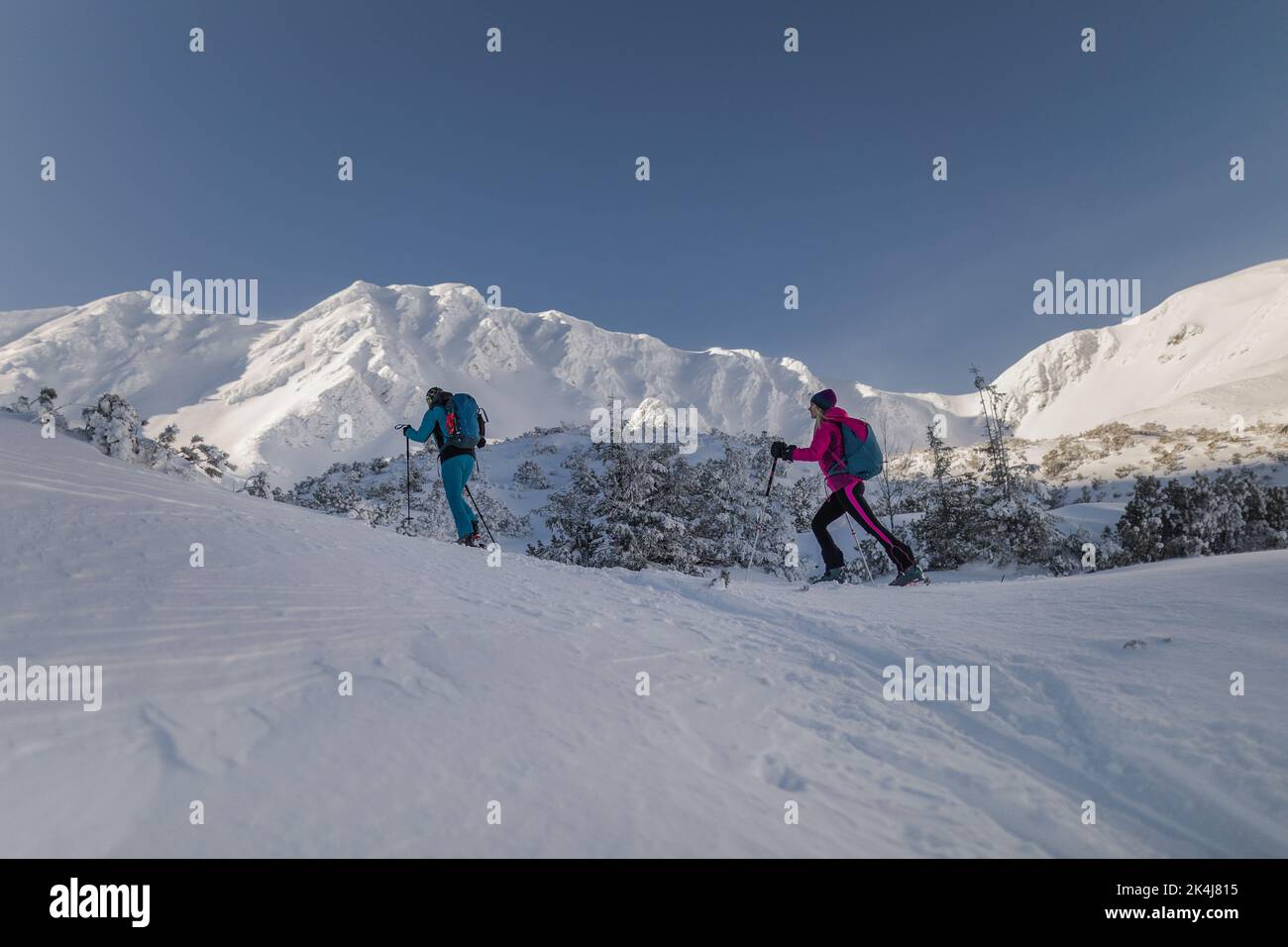 Low angle view of ski touring couple hiking up in mountains. Stock Photo