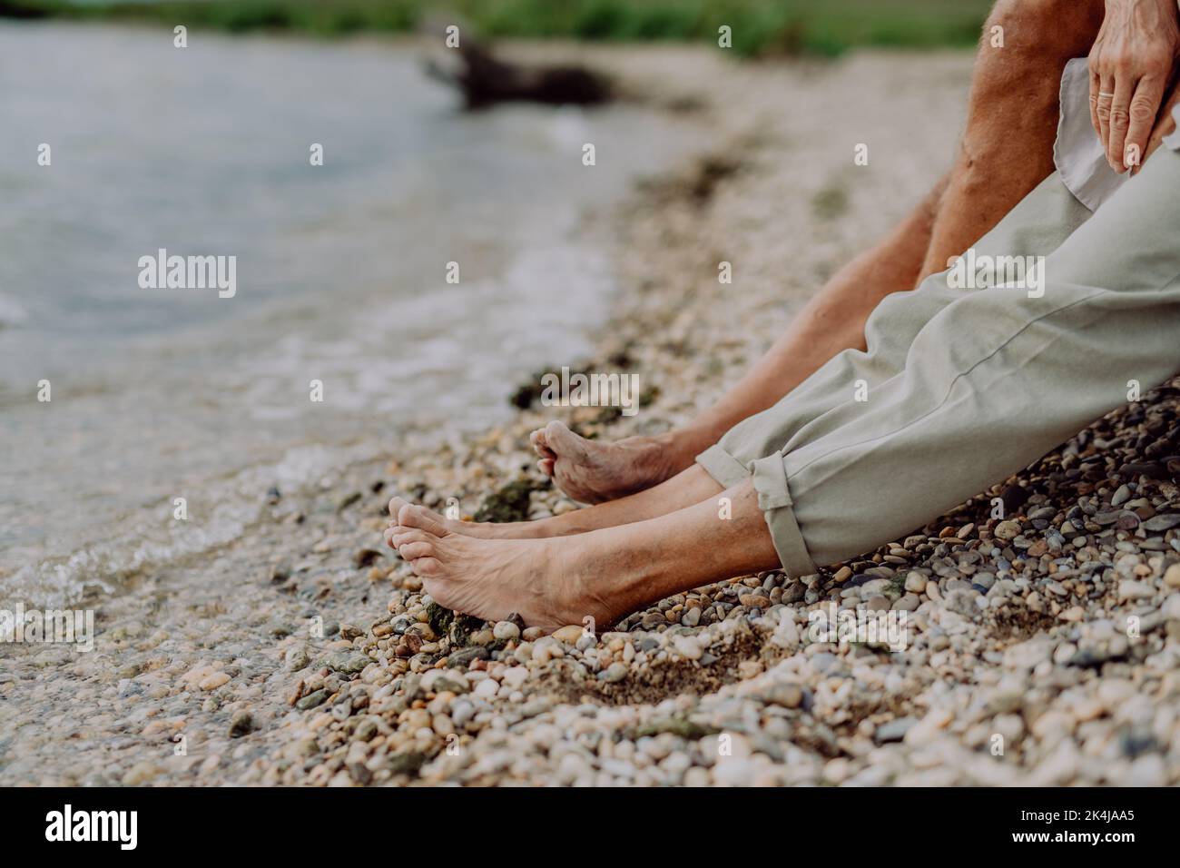 Close up seniors legs at beach near sea, resting together. Stock Photo