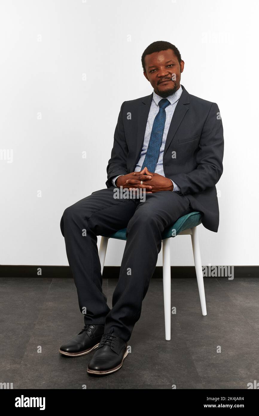 Smiling african american black man in business suit sitting on chair ...
