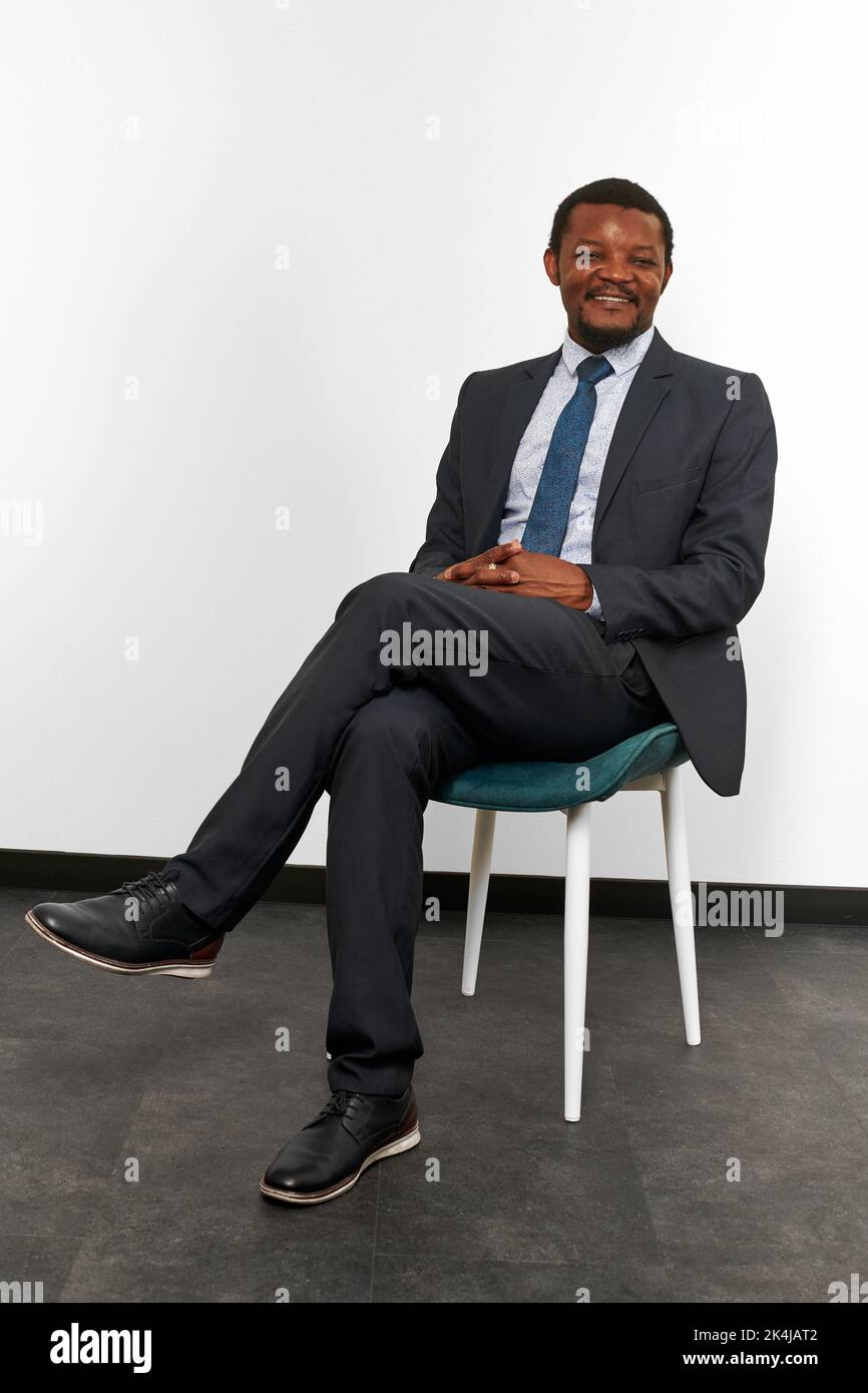 Smiling african american black man in business suit sitting on chair ...