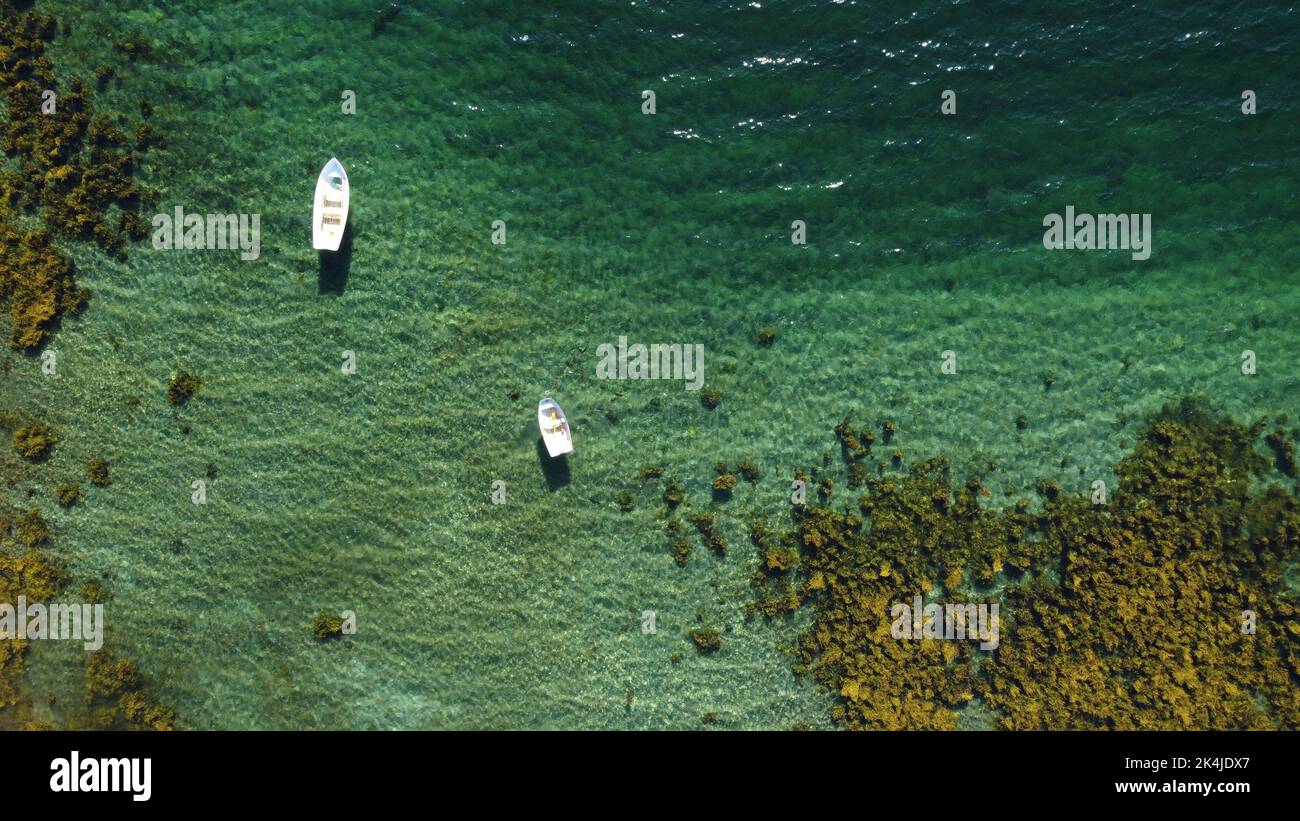 An aerial view of a mossy sea shore with boats on a bright sunny day