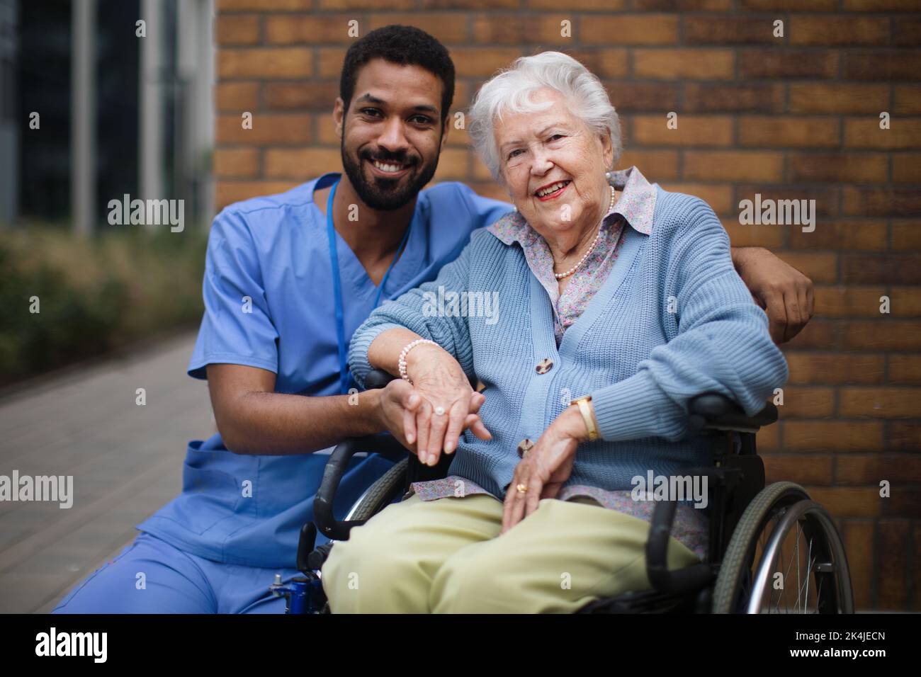 Happy senior woman at wheelchair spending time outside with her assistant. Stock Photo