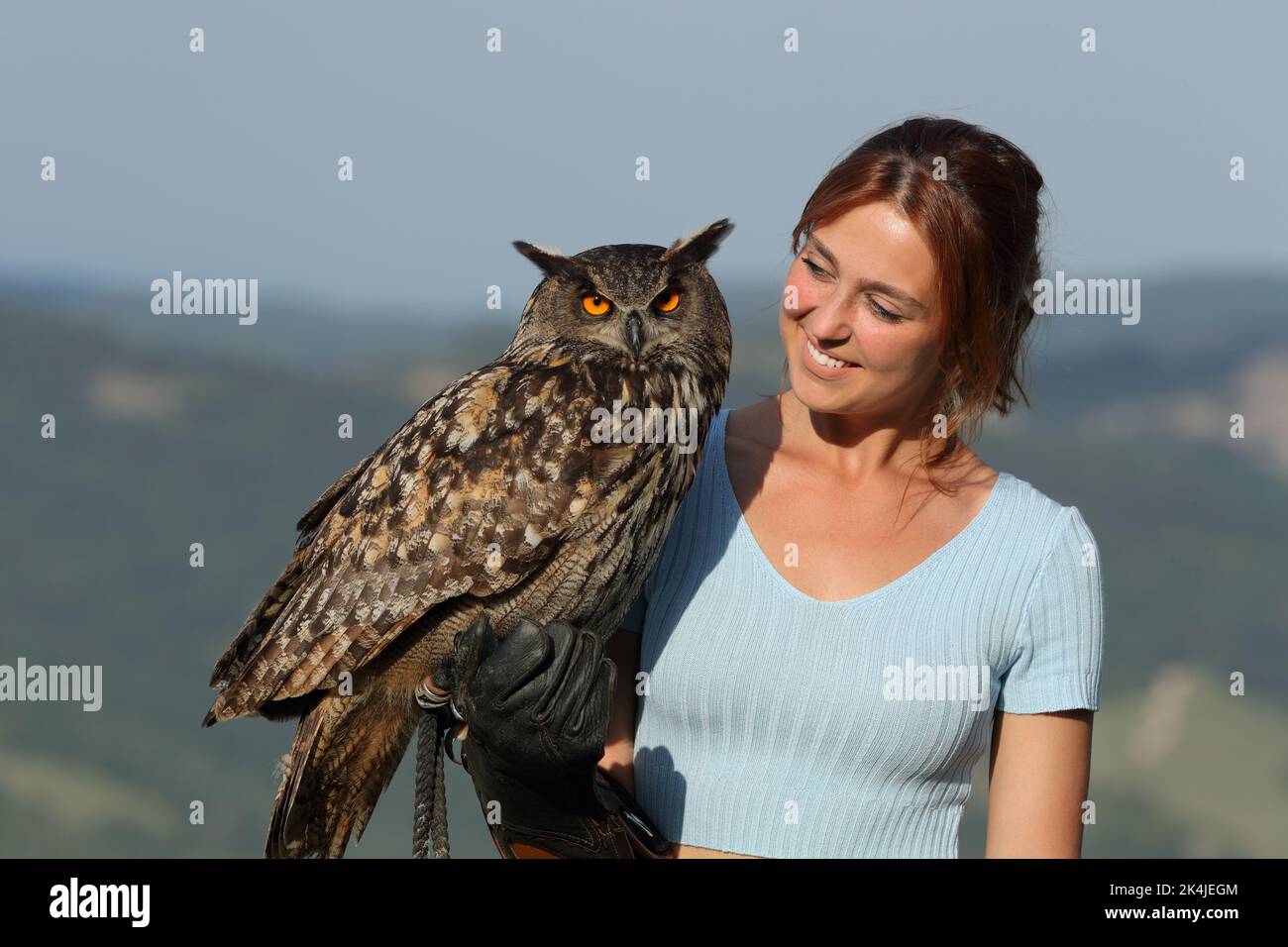 Happy falconer looking at a beautiful eagle owl outdoor Stock Photo