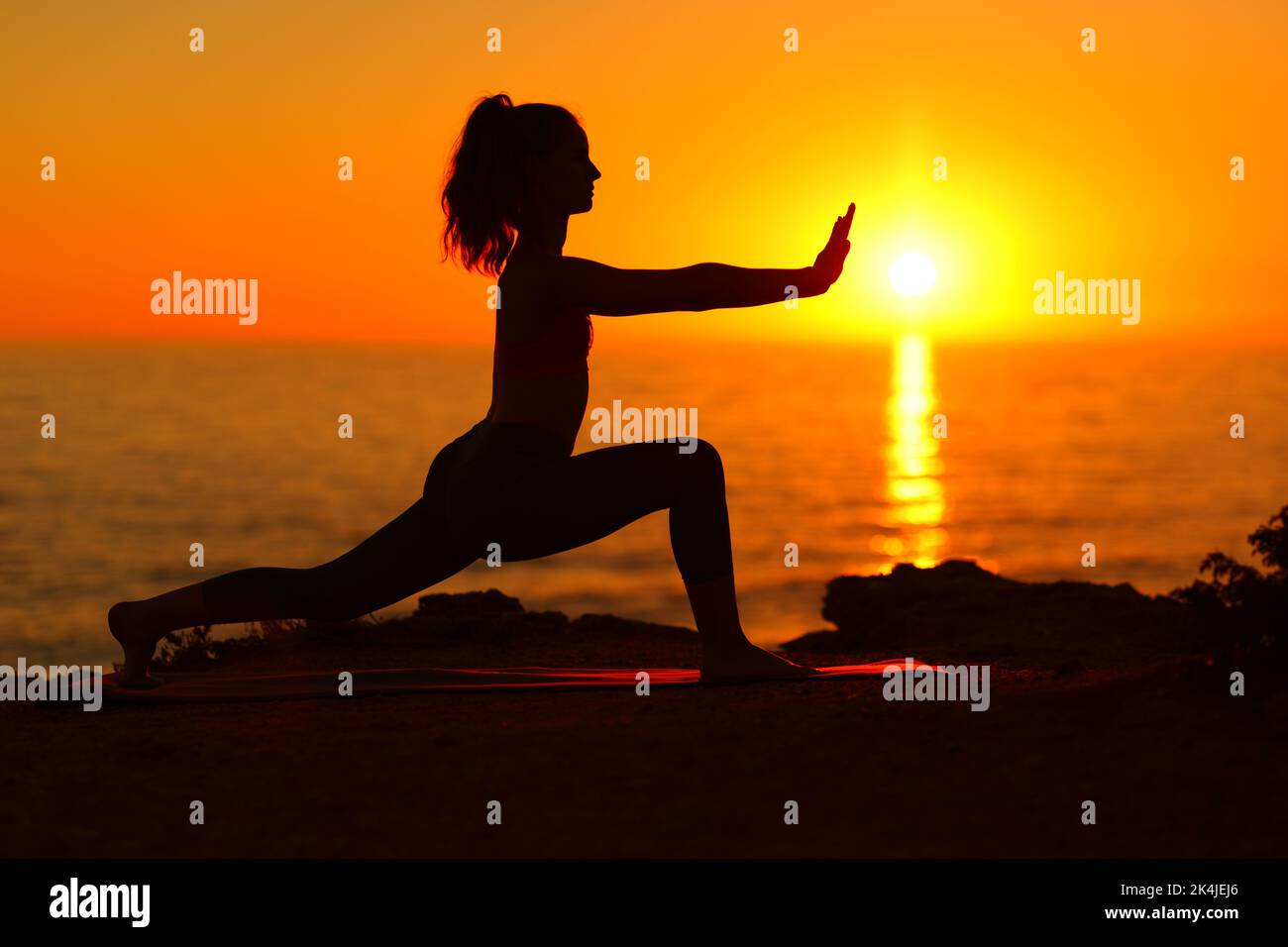 Profile of a woman silhouette doing tai chi at sunset on the beach Stock Photo