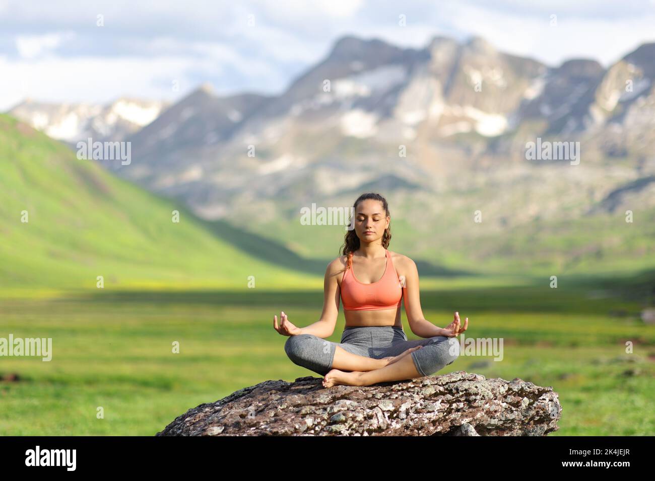 Front view portrait of a yogi on a rock doing yoga in amazing mountain Stock Photo