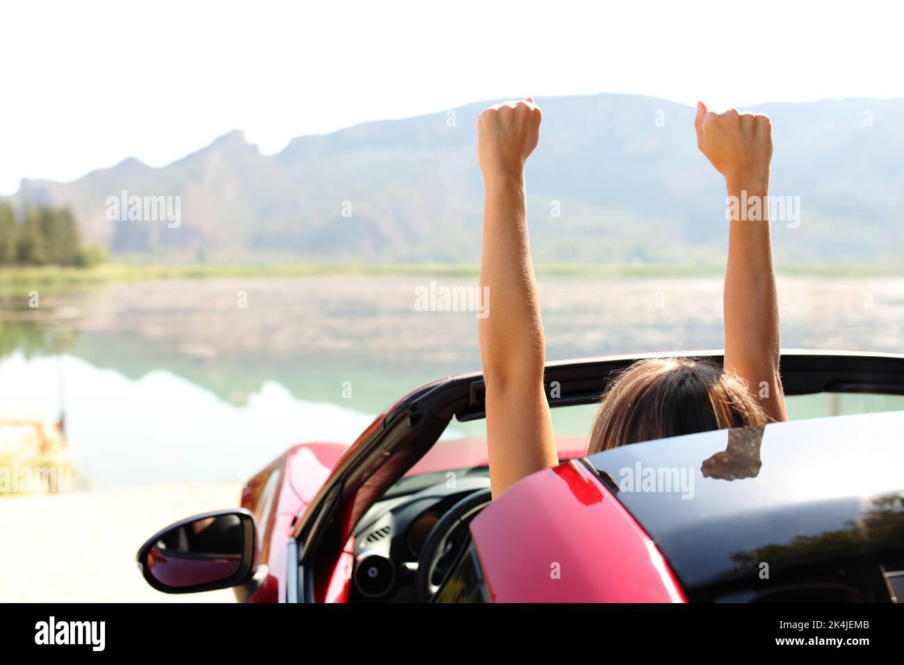 Back view portrait of a driver celebrating rsising arms in a convertible car Stock Photo