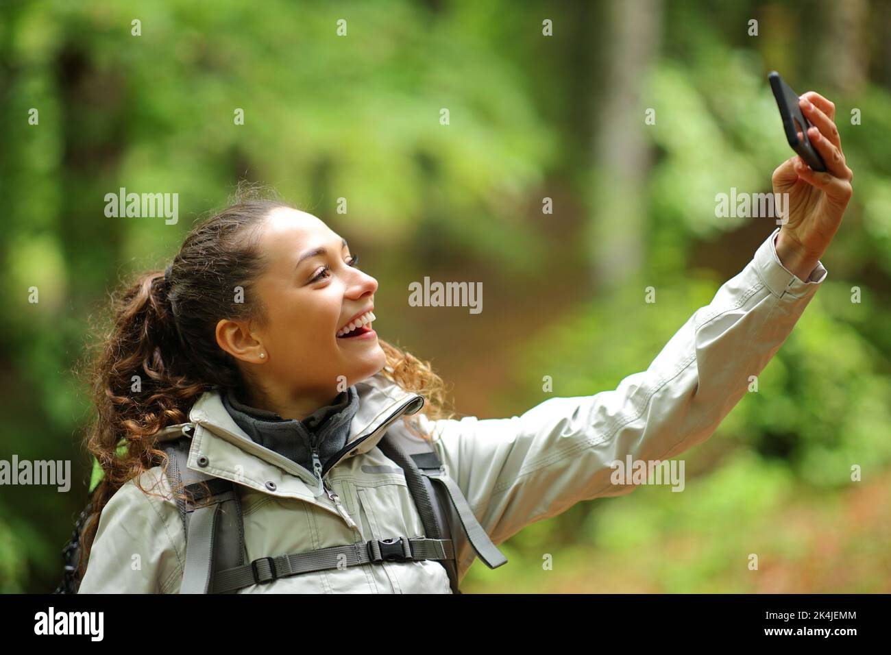 Happy hiker standing in a forest taking selfie with phone Stock Photo