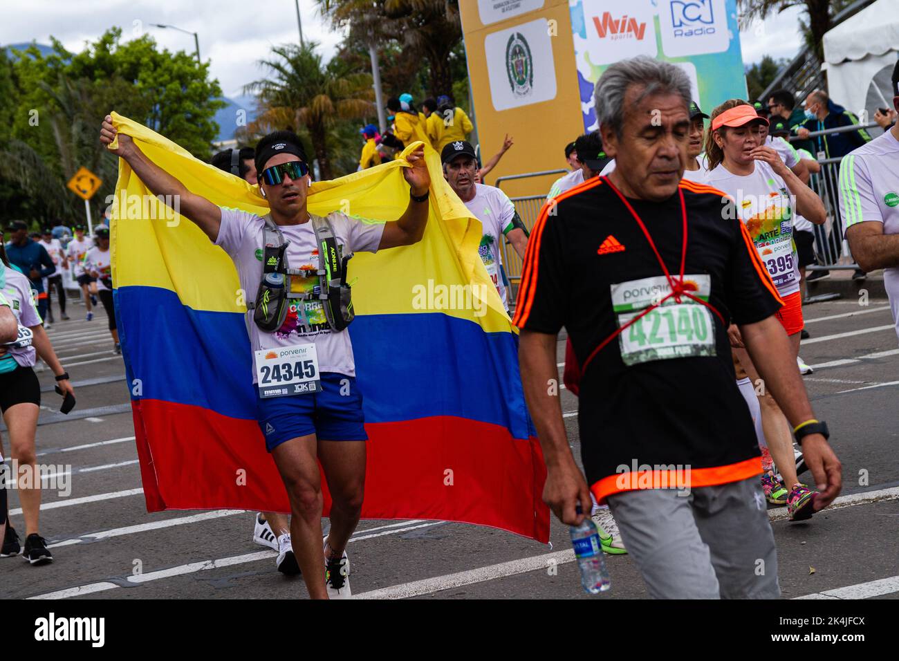 A runner finishes the race carrying a Colombian flag during the