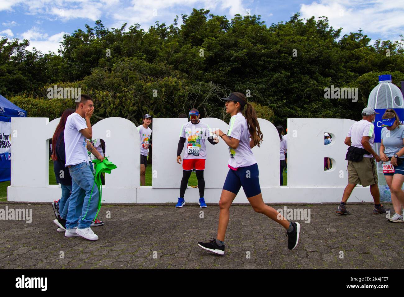 People run and pose on a sign with the acronym of Bogota's half