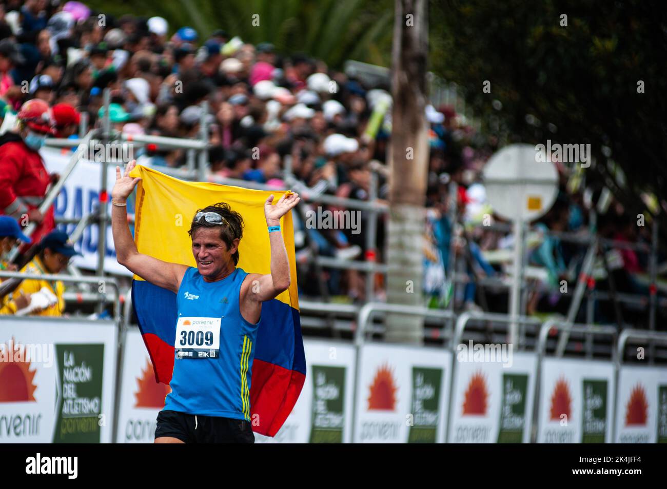 A runner finishes the race carrying a Colombian flag during the