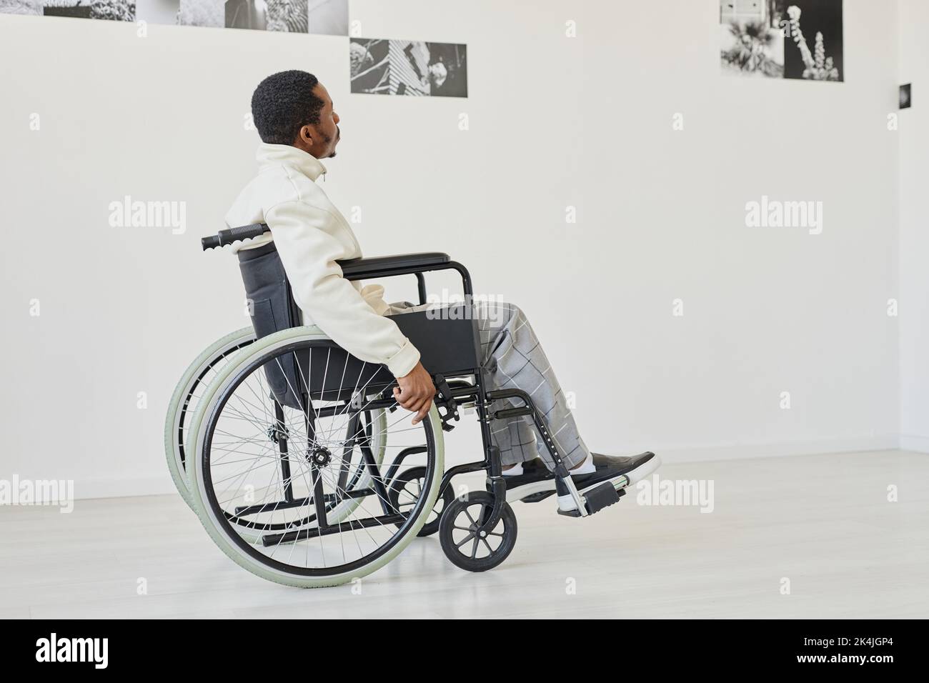 Black young man using wheelchair while visiting modern art gallery, copy space Stock Photo