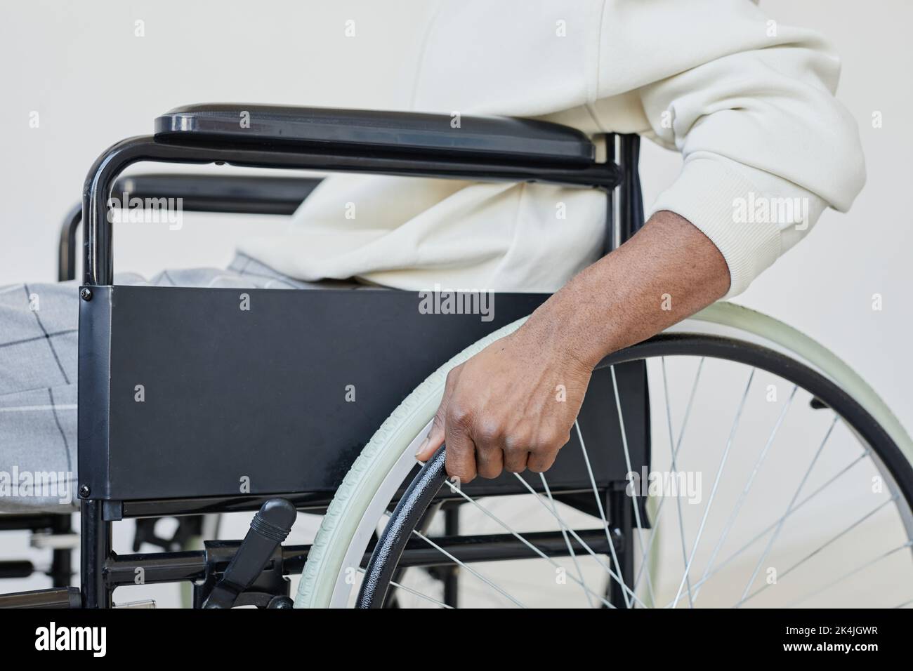 Side view closeup of young man using wheelchair against white, copy space Stock Photo