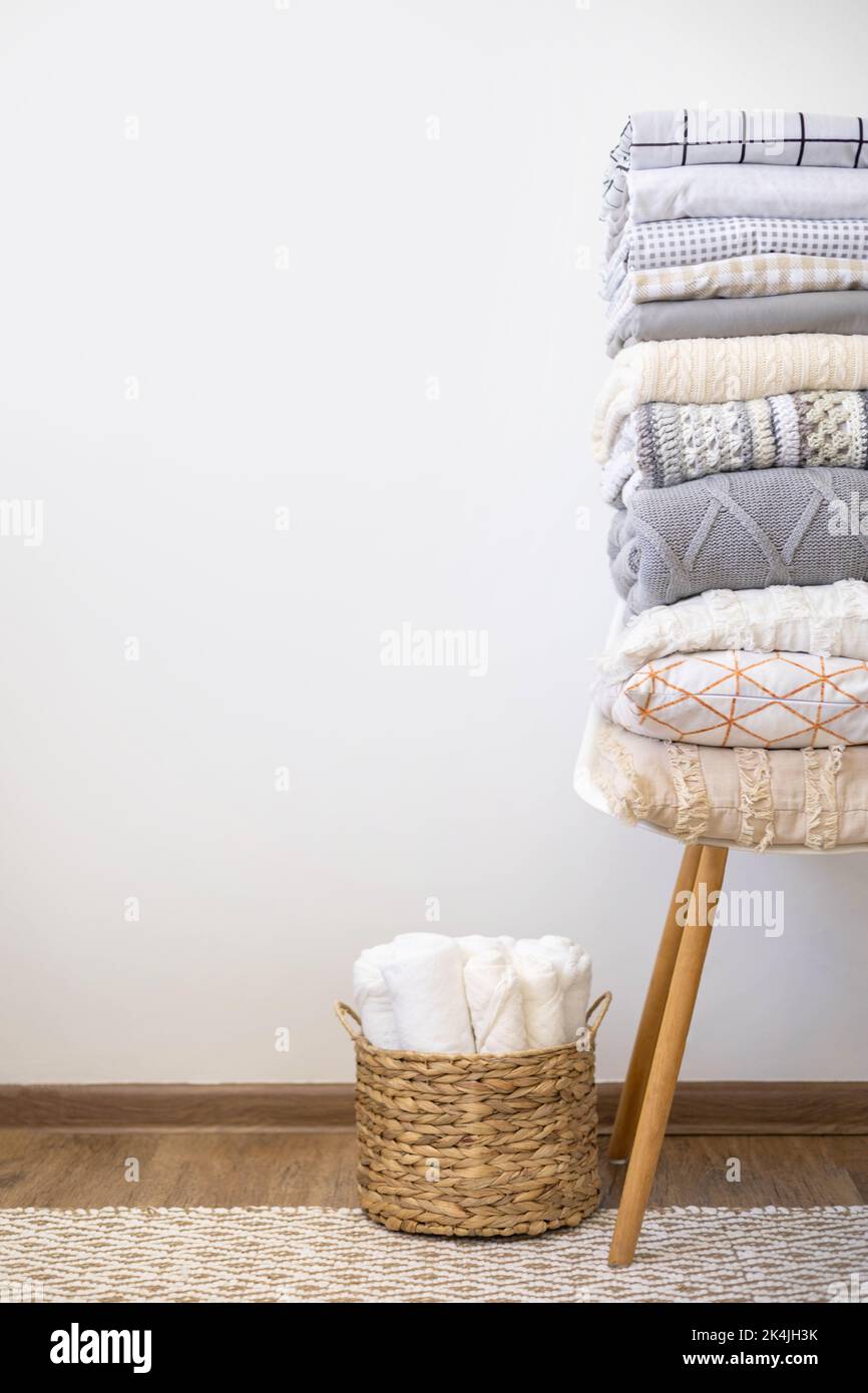 Neatly folded bed linens on chair minimalist white wall Nordic apartment wooden floor and carpet Stock Photo