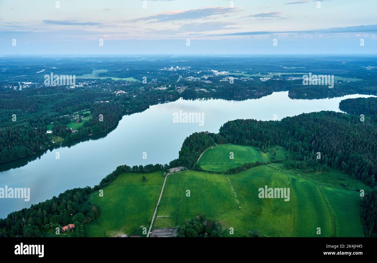 An aerial view of river surrounded by dense trees and greenery fields ...