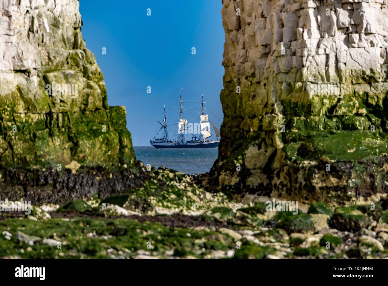 pic shows:  A tall ship in full sail passesKingsgate Bay near Broadstairs Kent today And could be spotted through the eye of Rock Arch by lucky early Stock Photo