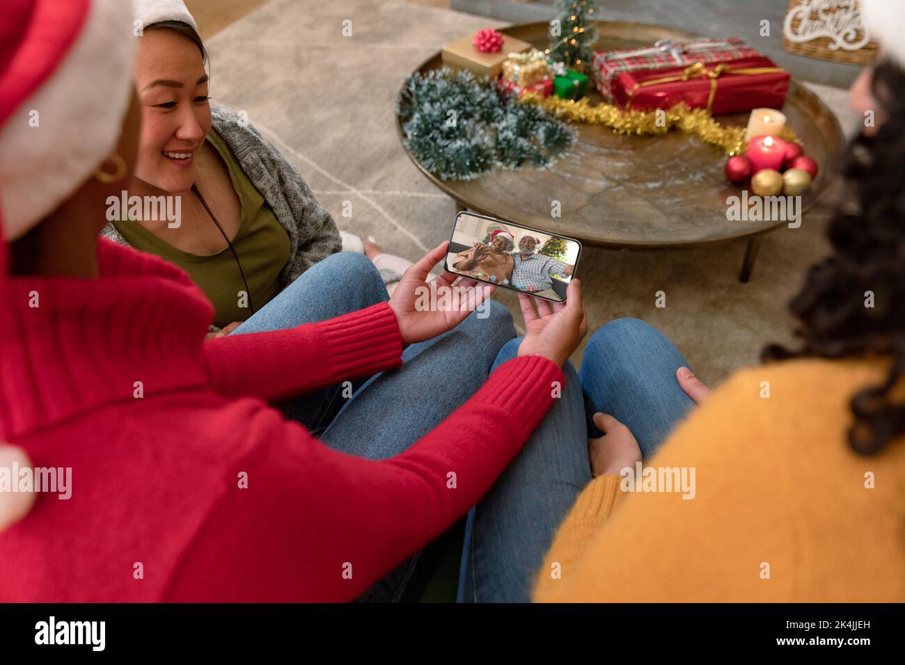 Biracial family in santa hats on christmas smartphone video call with ...