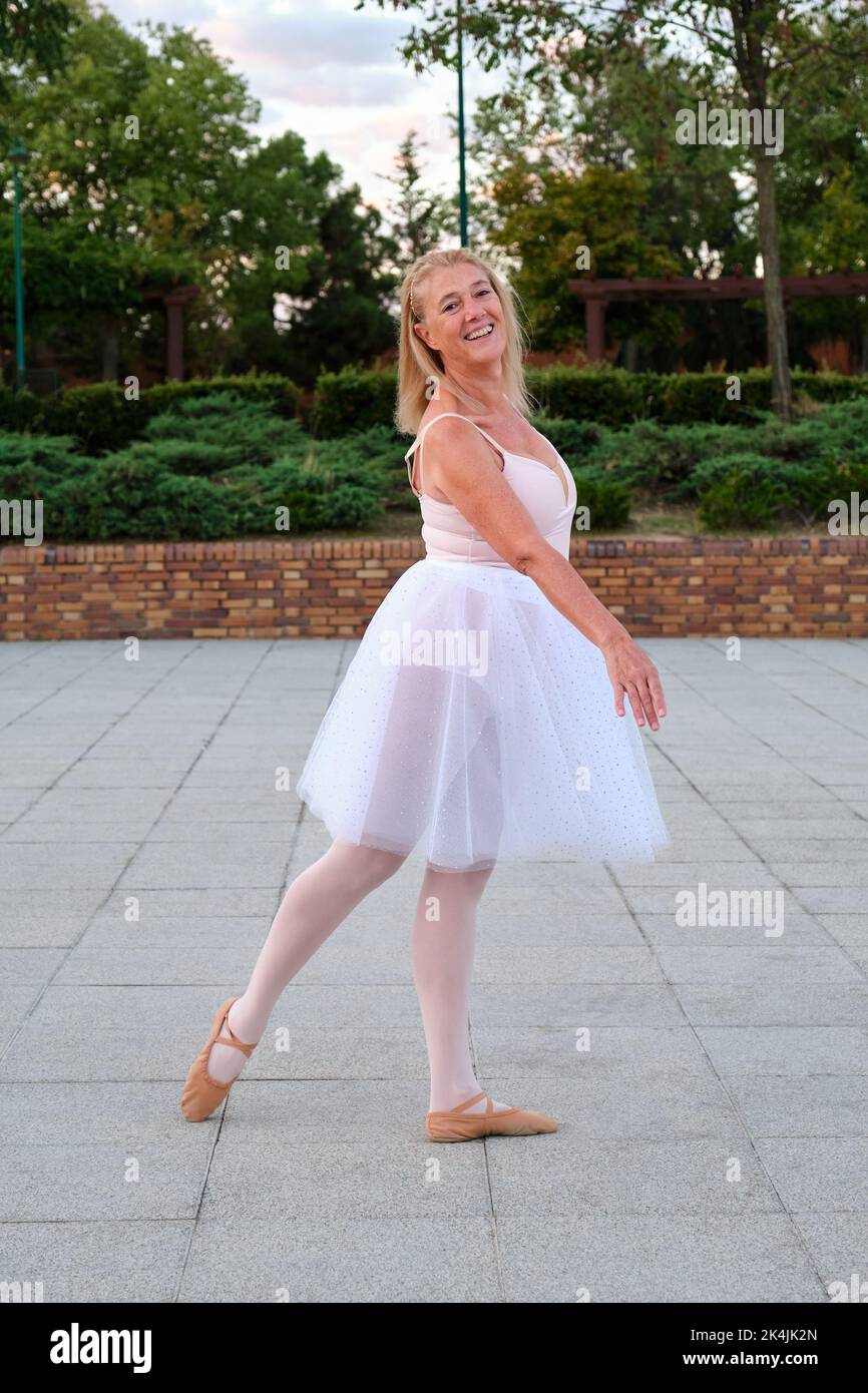 Mature woman dancing ballet in a park at street. Stock Photo