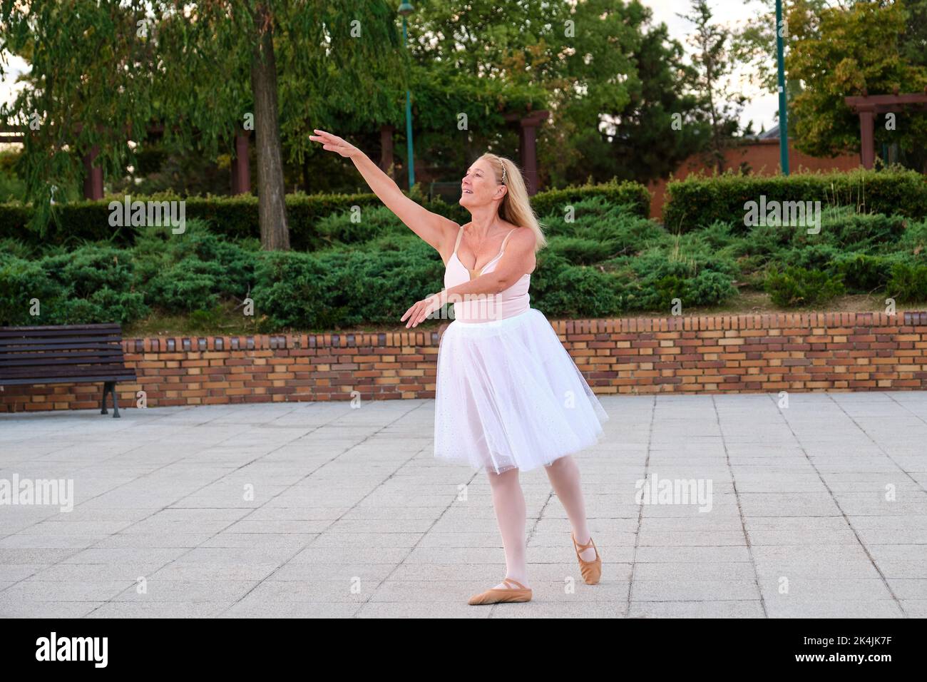 Mature woman dancing ballet in a park at street. Stock Photo