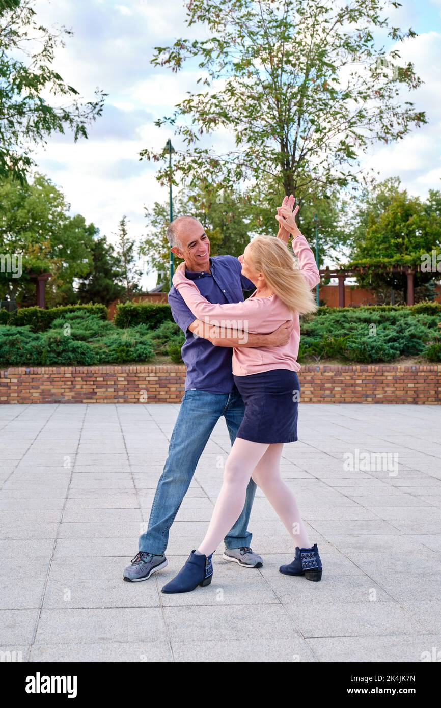 Mature couple dancing tango in a park at street. Stock Photo