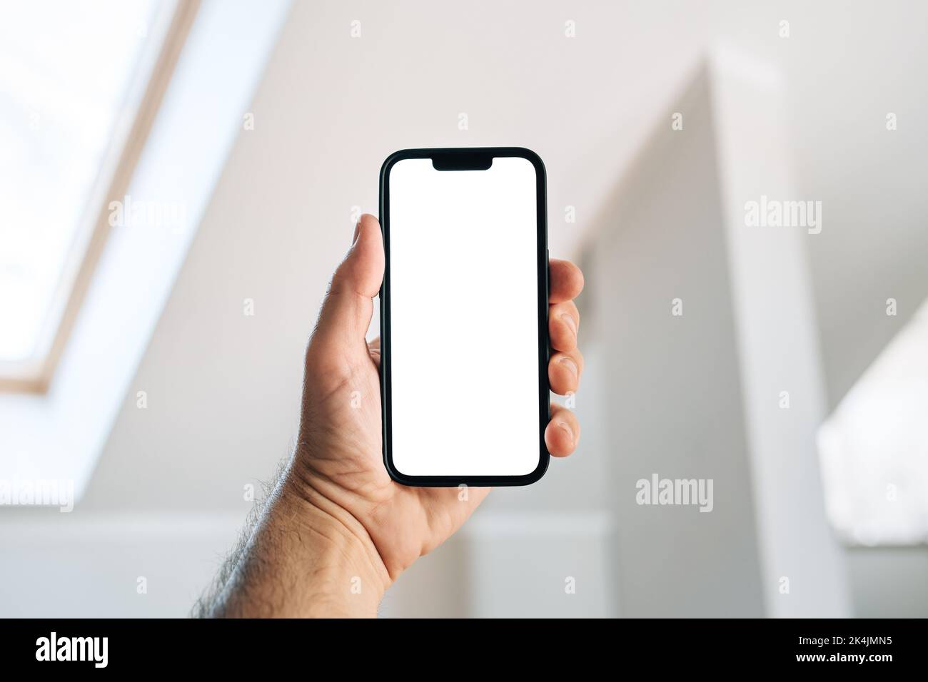 Tourist in hotel room holding smartphone with blank mockup screen for booking and reservation app or accommodation rating service Stock Photo