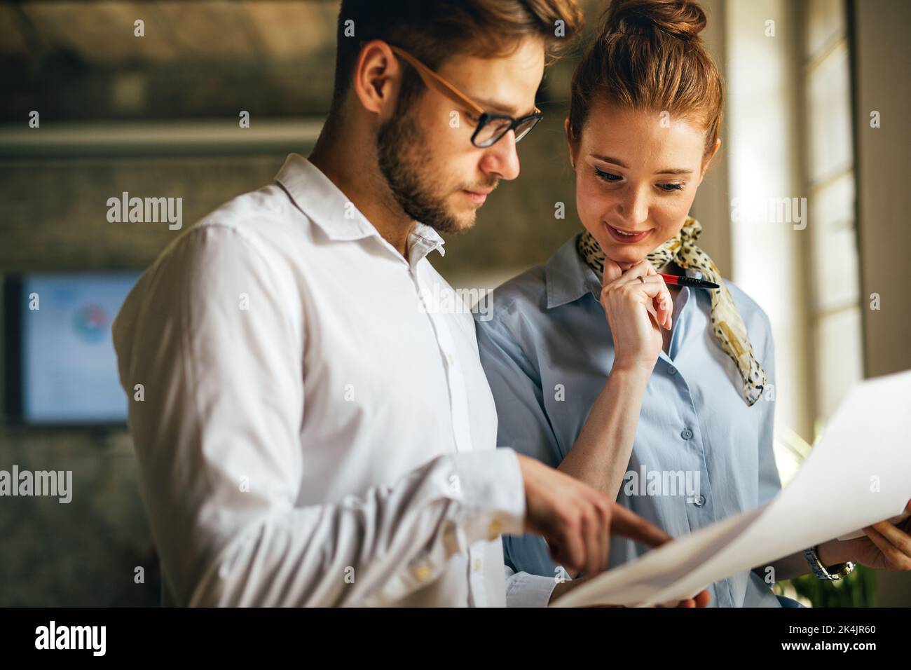 Portrait of two young business people talking about documents in office Stock Photo