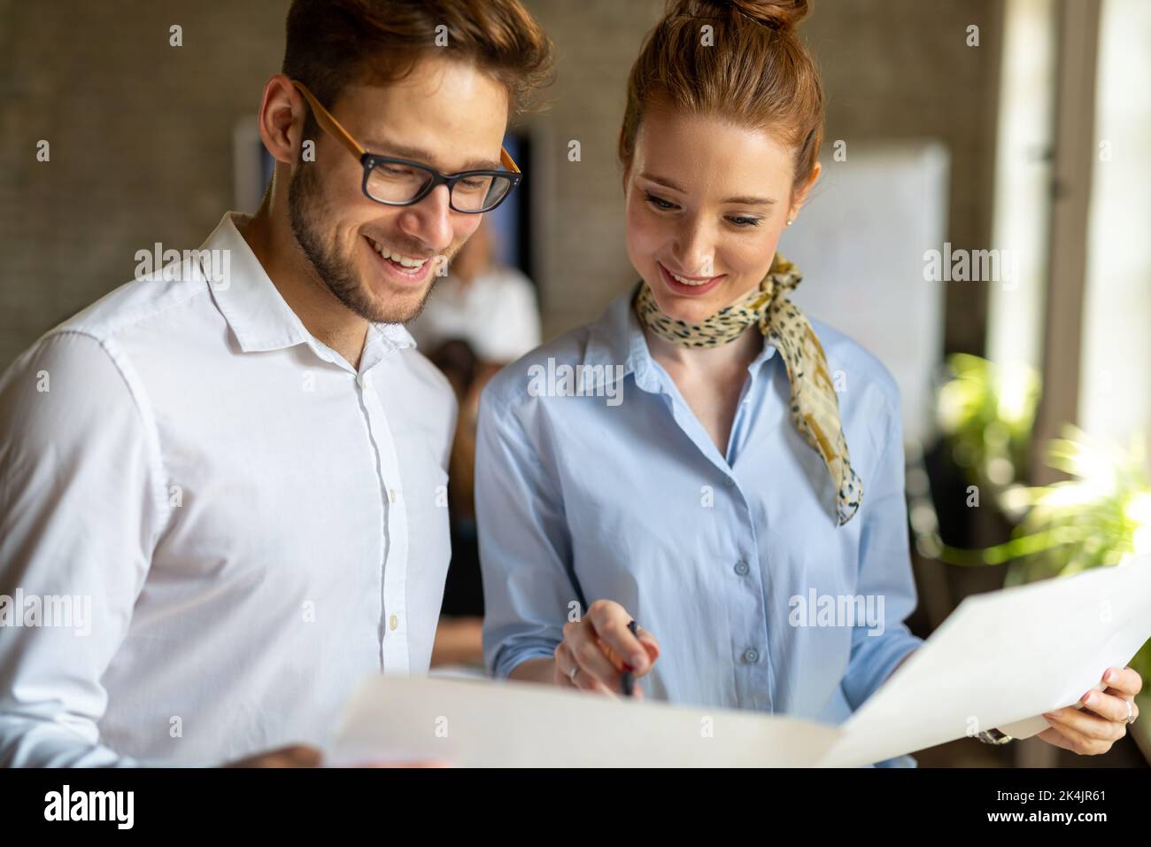 Portrait of two young business people talking about documents in office Stock Photo