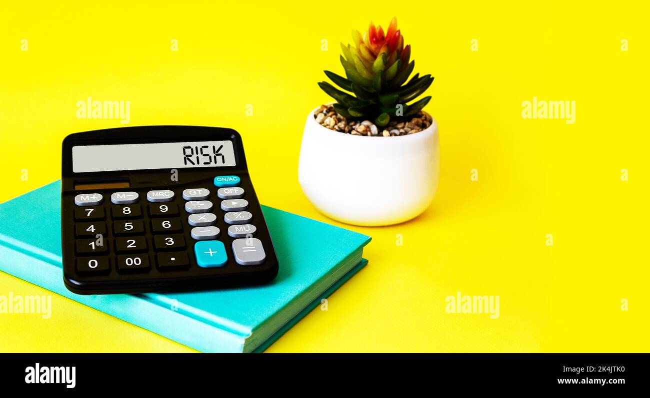 insurance or risk concept. Word Risk on calculator display and yellow background Stock Photo