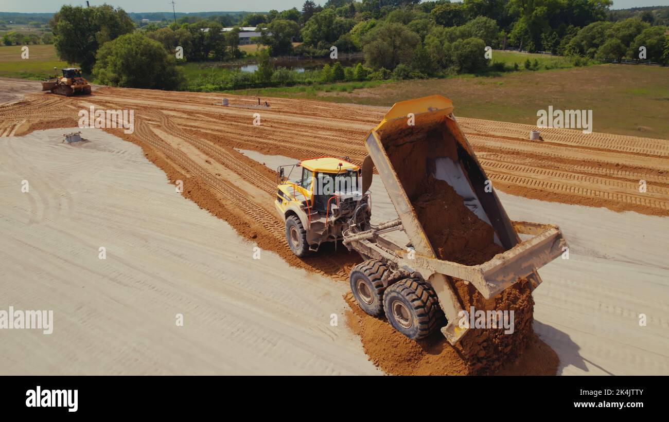 Industrial dumper truck working on a highway construction site, unloading soil. Bulldozer leveling the ground. Warsaw, Poland. . High quality photo Stock Photo