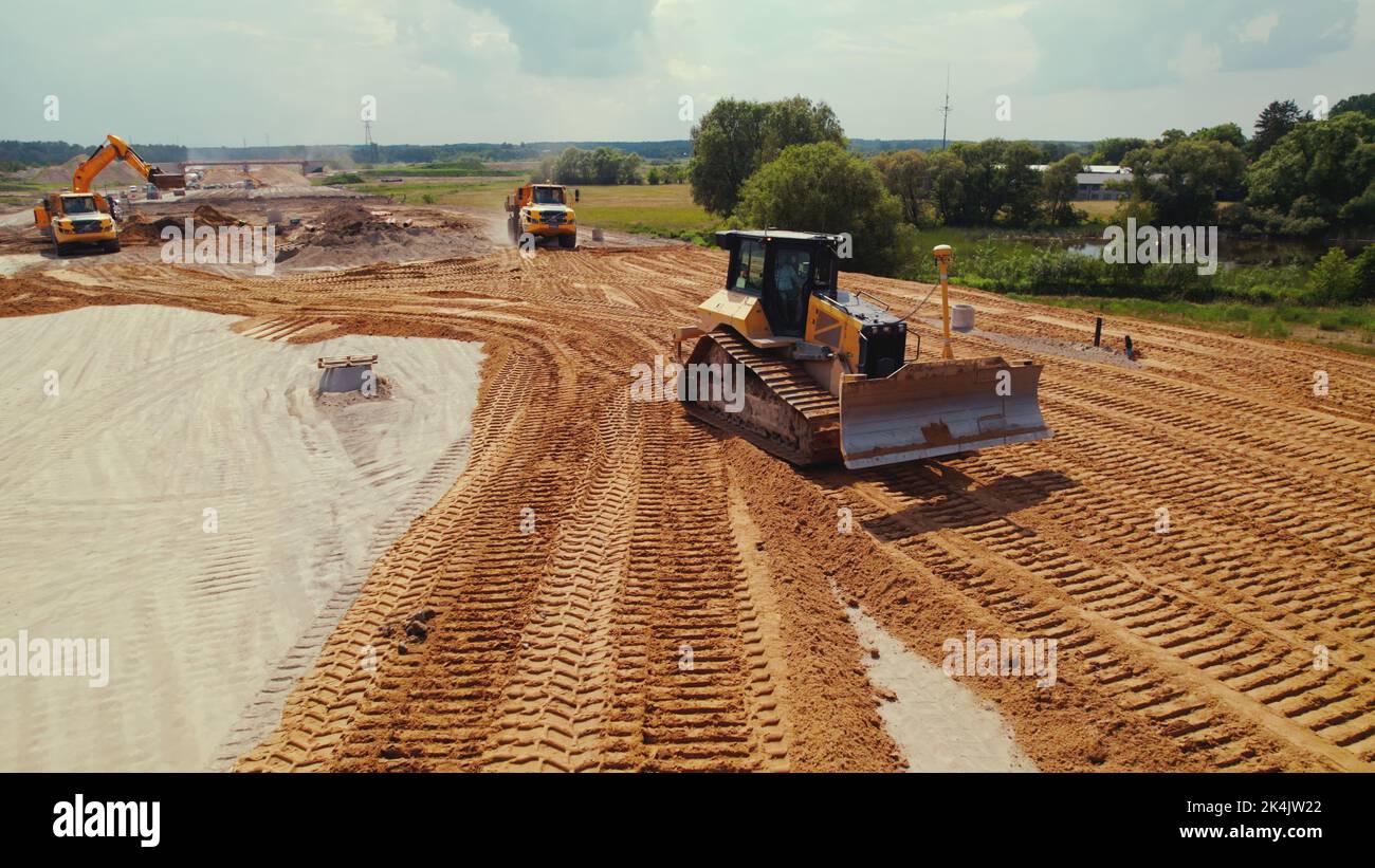 Active work on a road building site. A dumper truck with earth in a body, transporting it. Heavy construction machinery. Warsaw, Poland. Top aerial view. High quality photo Stock Photo