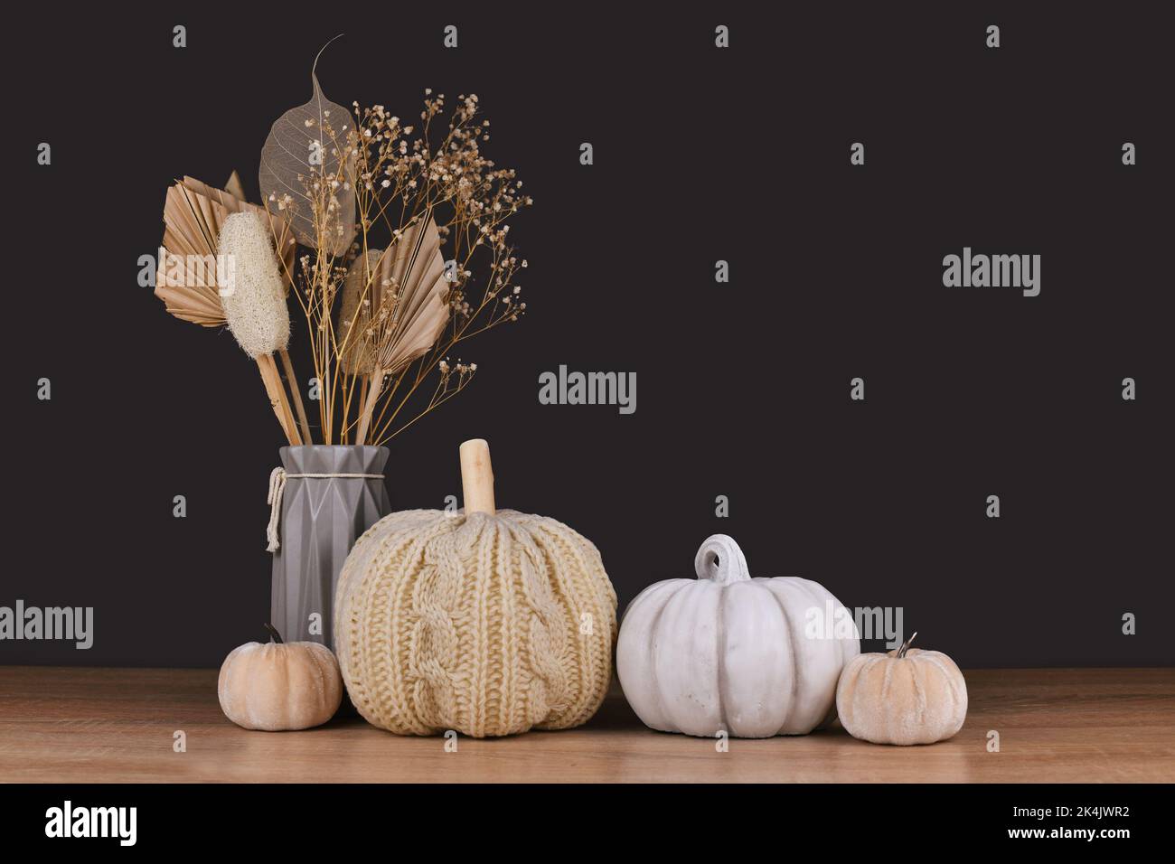 Fall decoration with boho style knitted beige pumpkin and gray stone pumpkin on dark backgroun Stock Photo