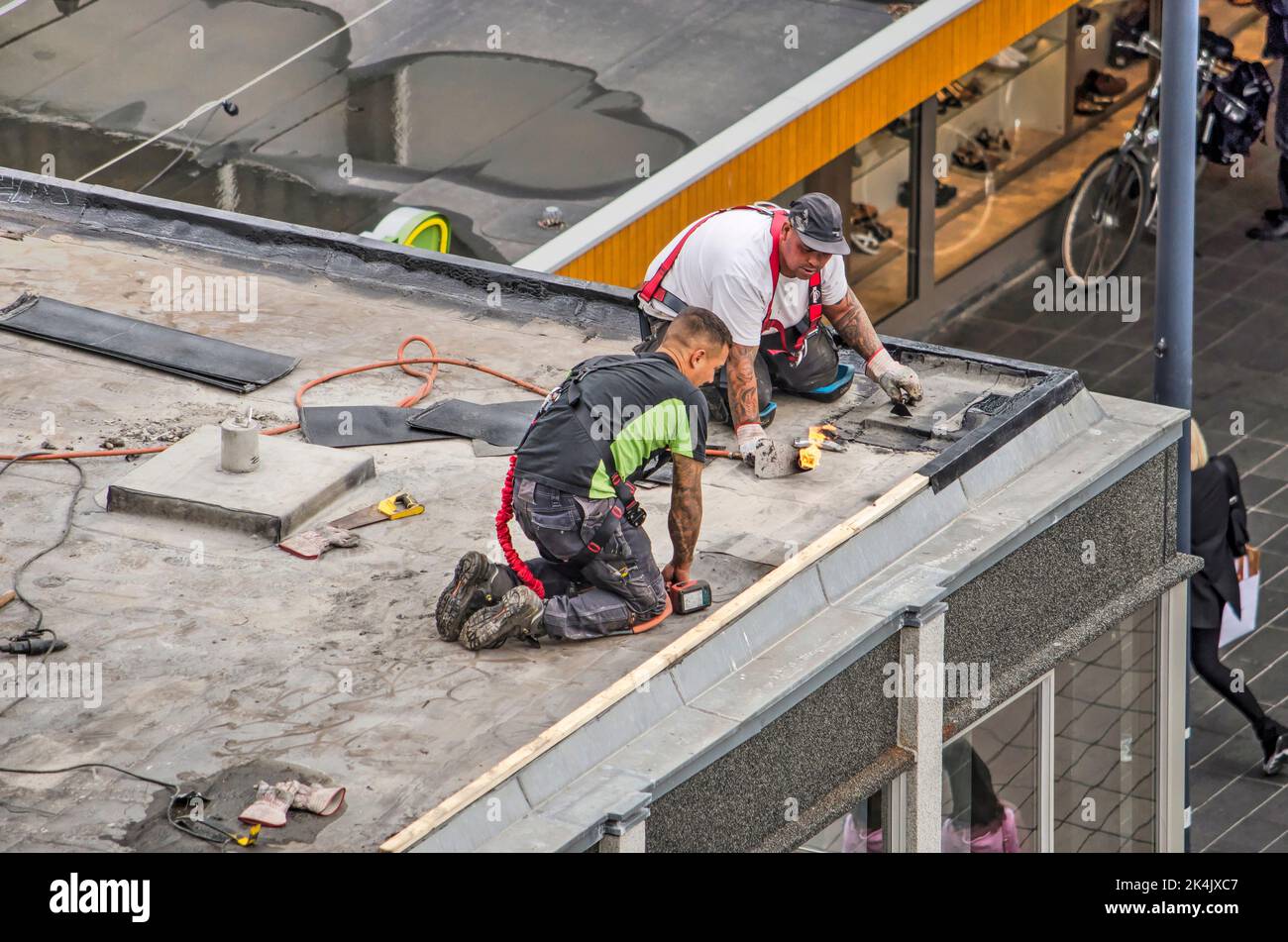 Rotterdam, The Netherlands, July 1, 2020: two workers doing maintenance work on a roof at Lijnbaan shopping street Stock Photo