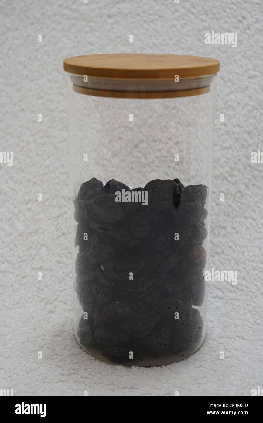 black prunes in glass jar on textured white background Stock Photo Alamy