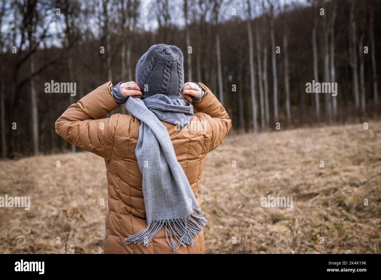 Wind and cold weather in fall season. Woman wearing coat, scarf and knit hat outdoors Stock Photo