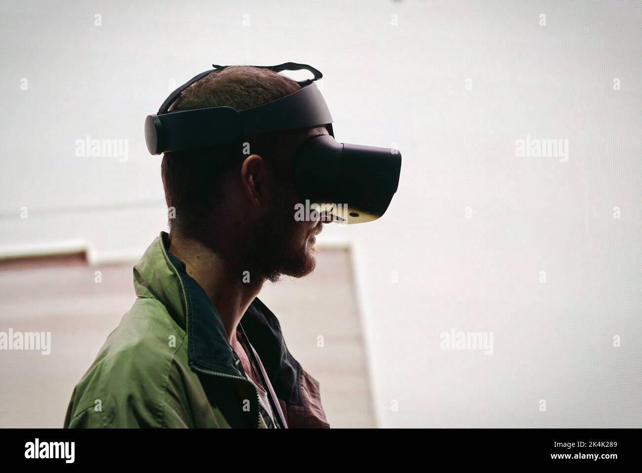 Virtual reality exhibit. Young man wears virtual reality goggles experiences a metaverse encounter. Turin, Italy - September 2022 Stock Photo