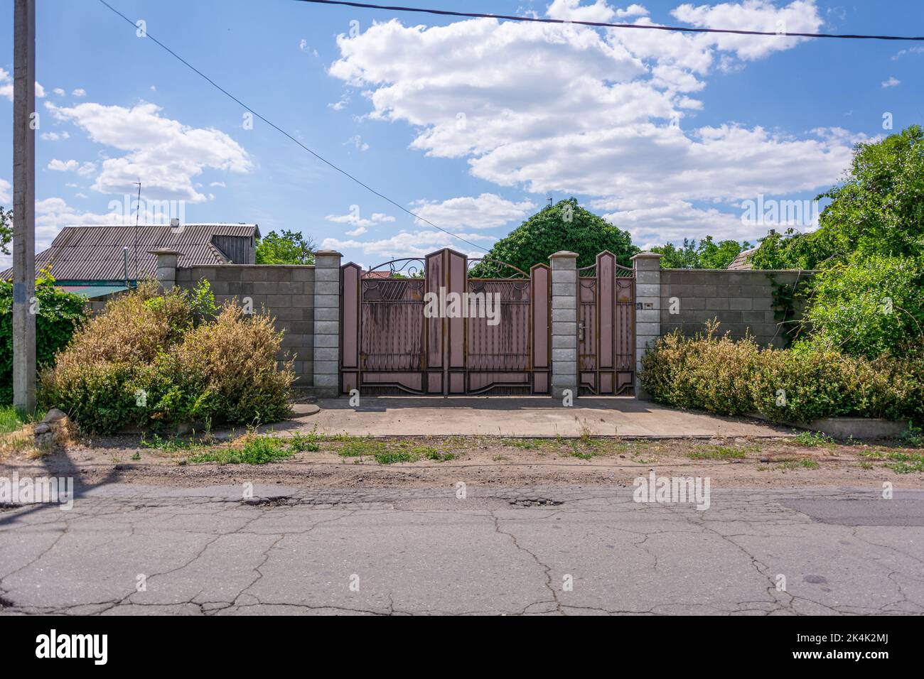 Fence of a private house. View from the street on fence with patterned iron gates encloses a private house in Transnistrian village Stock Photo