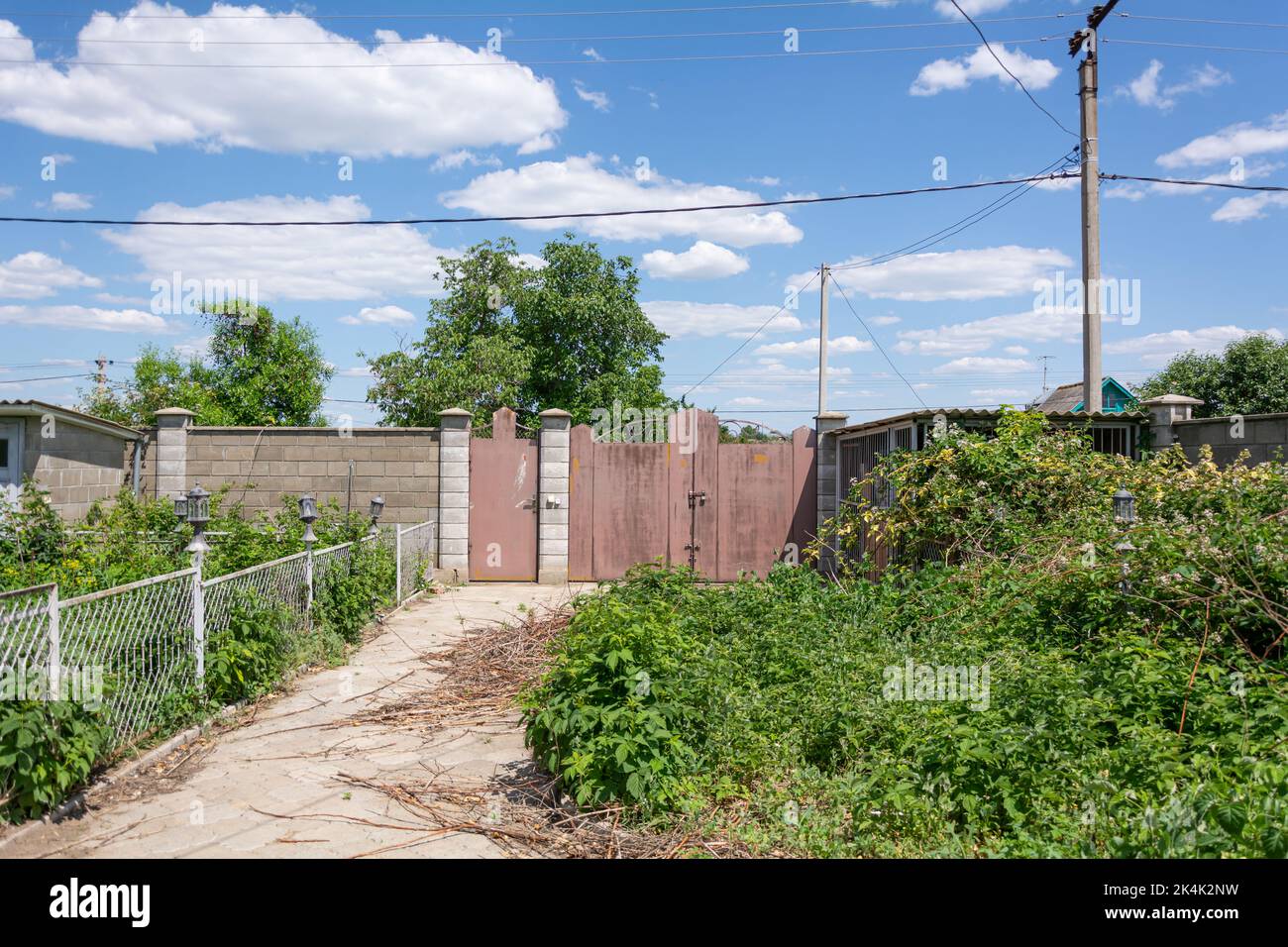 Fence of a private house. View from the yard on fence with patterned iron gates encloses a private house in Transnistrian village Stock Photo